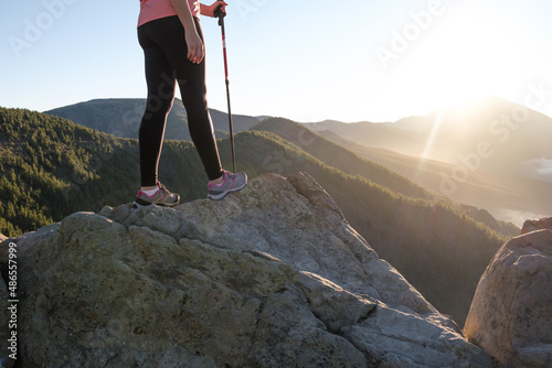 woman with the sun in the background on top of the mountain