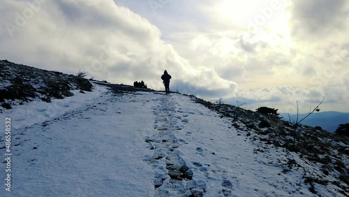 Silhouette hiker man walking towards cloudy sky on mountain in winter. slow motion video