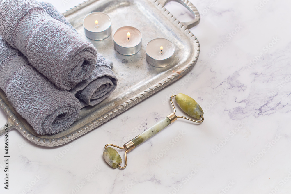 jade facial roller on white marble table. Flat lay, spa concept jade facial roller on white marble table. Flat lay, spa concept