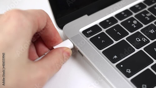 Person hand pull out or extract a USB-C cable charger from computer or laptop after charging. Close-up view