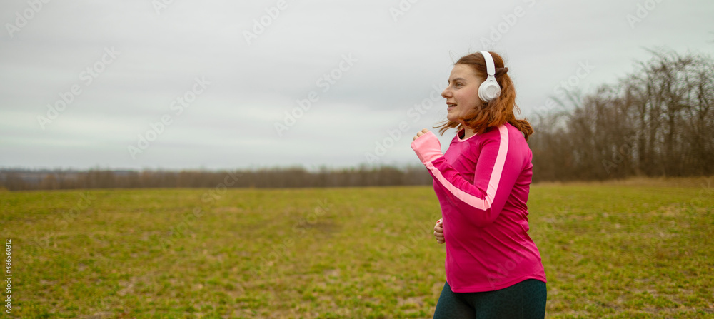 Fat woman in sportswear and wireless headphones running in the park. Weight loss concept Fat woman in sportswear and wireless headphones running in the park. Weight loss concept