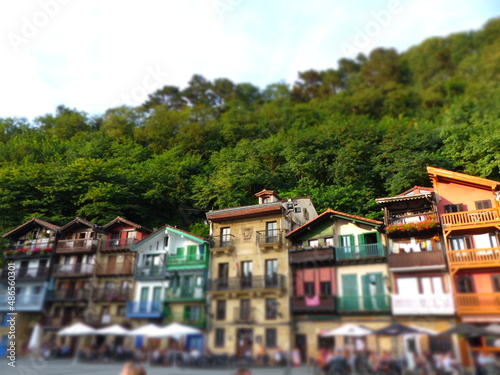  Plaza de Santiago, in the town of Pasajes, (Pasaia). Traditional houses with facades of different colors and wooden balconies. In the background leafy trees. San Sebastian, Guipuzcoa, Basque Country.