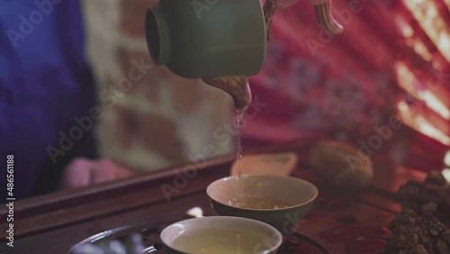 A man pours tea into tea cups on a wooden tray in a tea room photo