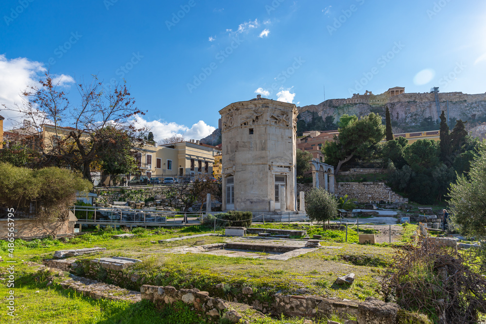 ATHENS, GREECE - DECEMBER 19, 2021: Roman Agora with ancient columns and Wind tower with blue sky.