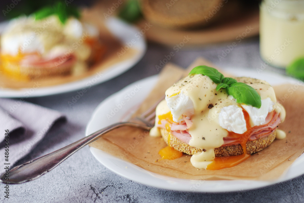 Egg benedict sandwiches - muffin with poached egg, ham and hollandaise sauce