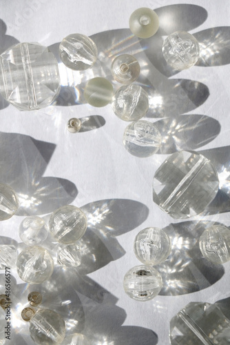 Various transparent beads on white background, illuminated by sunlight and reflectiing light. Flat lay. photo