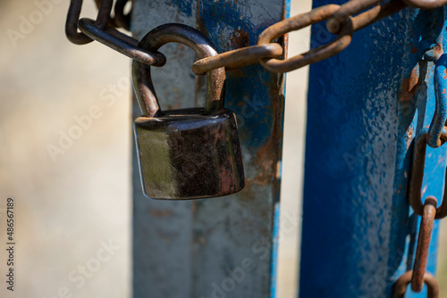 Old rusty padlock and chain on metal door. Old locked gate with chains.