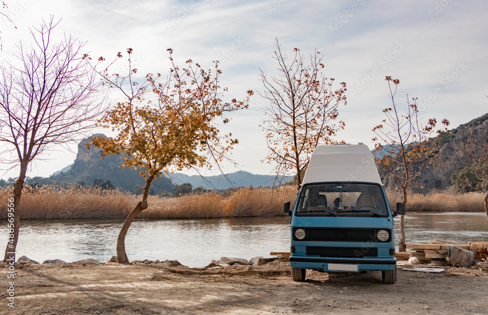 Sweet blue caravan parked by the lake. Autumn season. Naked tree. Beautiful landscape. Sweet blue caravan parked by the lake. Autumn season. Naked tree. Beautiful landscape.