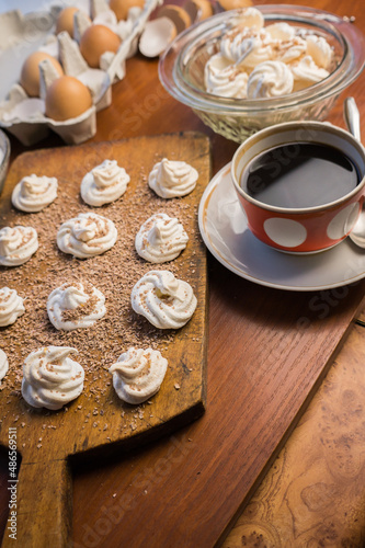 Delicious crispy homemade egg meringue sprinkled with grated dark chocolate  prepared with love on a wooden background  crunchy dessert for coffee or tea. 