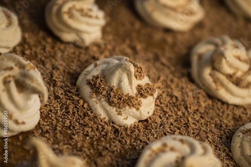 Delicious crispy homemade egg meringue sprinkled with grated dark chocolate, prepared with love on a wooden background, crunchy dessert for coffee or tea. 