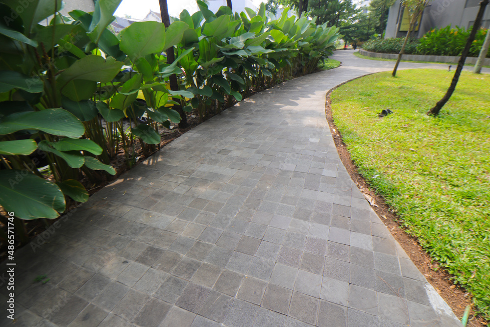 Pathway with concrete paving bricks and green trees in a shopping center park in Bandung