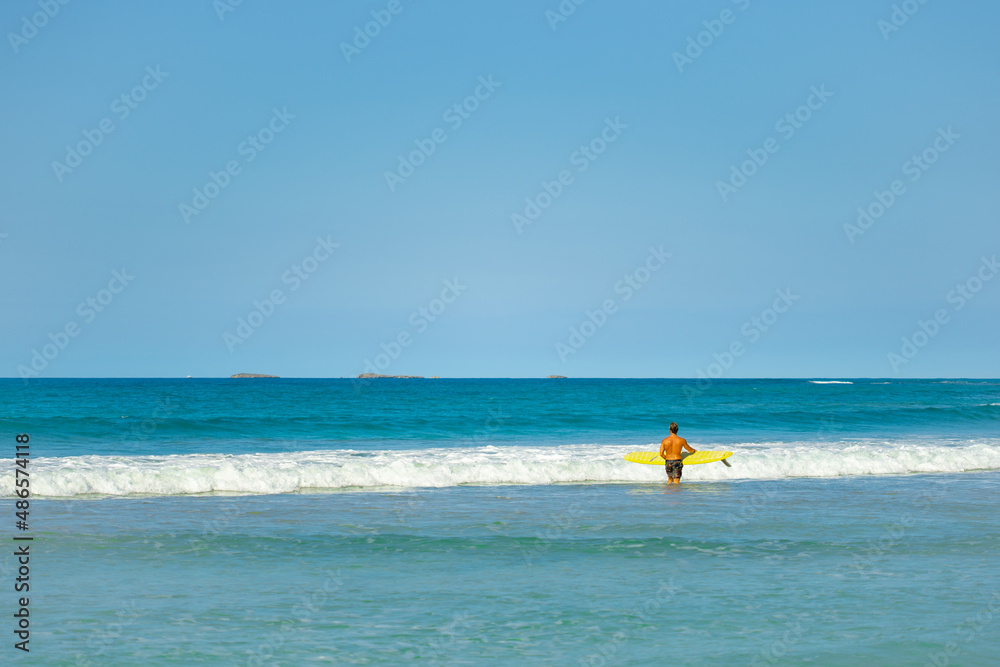 Sunny coast of the Indian Ocean on a sunny day. High waves for surfing. Cruise. Beautiful blue sea against the blue sky. A man with a surf in the sea.