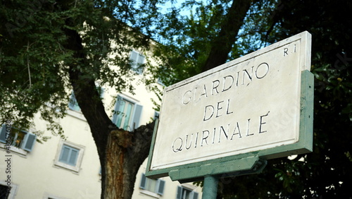 Tableau sur toile Street plaque in marble of the Quirinale garden, with buildings in the blurred b