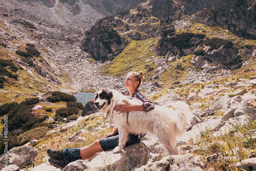 woman with white dog sitting on mountain top in summer landscape slow travel and freedom concept