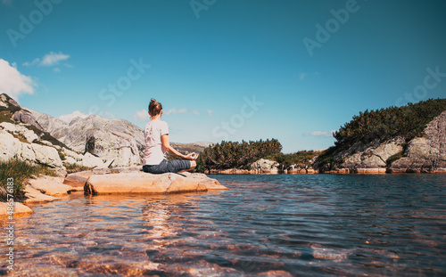 healthy young woman doing yoga in mountain landscape by lake