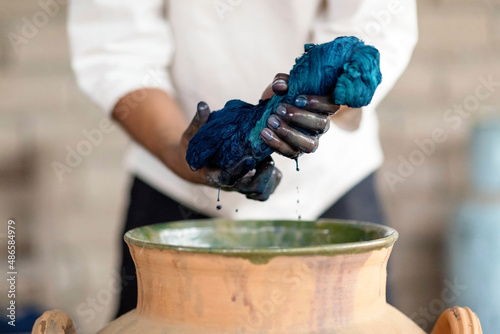 Two hands wring out fabric while indigo dyeing.