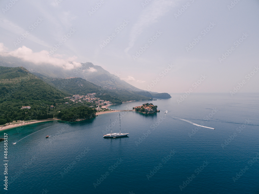 Aerial view of a sailing yacht against the backdrop of Sveti Stefan Island