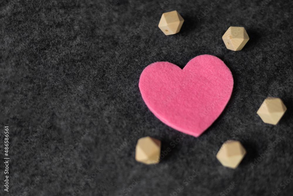 Fototapeta premium Pink felt heart on a dark gray background. scattered wooden cubes. St. Valentine's Day, Valentine's Day. top view