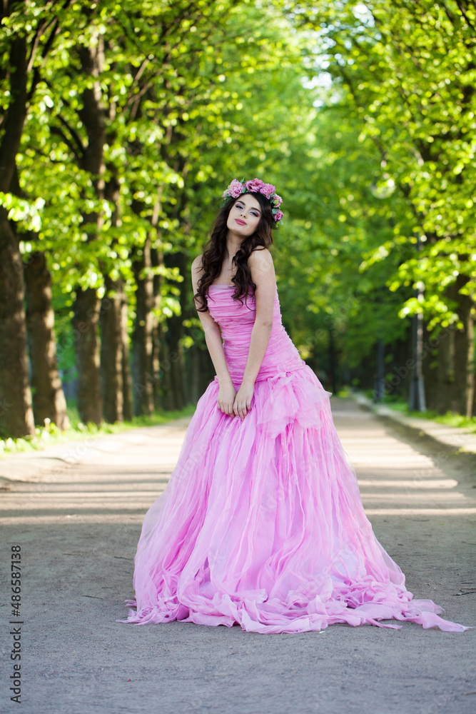 Perfect fashionable celebrity woman in pink dress posing outdoor on summer nature background