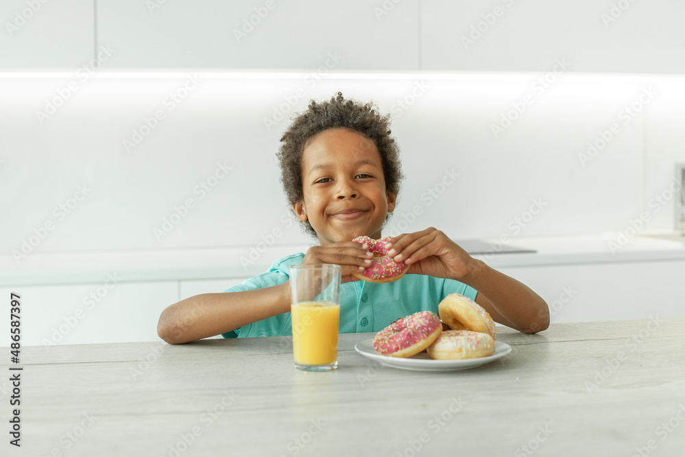 Portrait of happy child boy drinking orange juice and eating donuts Portrait of happy child boy drinking orange juice and eating donuts
