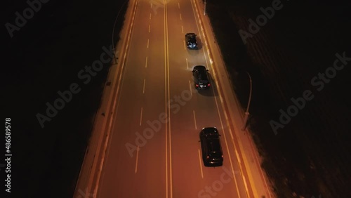  Aerial shooting of 3 black SUV cruising on motorway at night