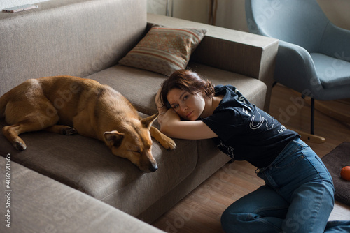 tired girl near a sleeping dog on the couch
 photo