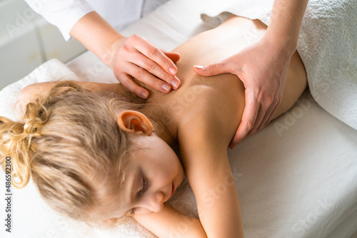 a woman gives a massage to a little girl, children's massage, prevention of scoliosis, osteopathy