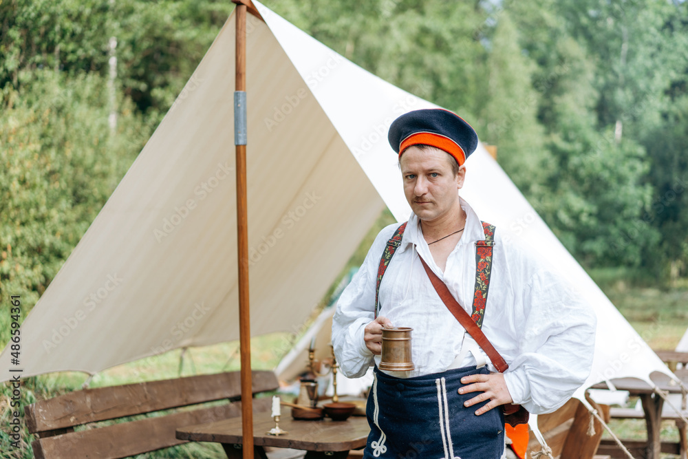 The soldier drinks water from a cup while resting.