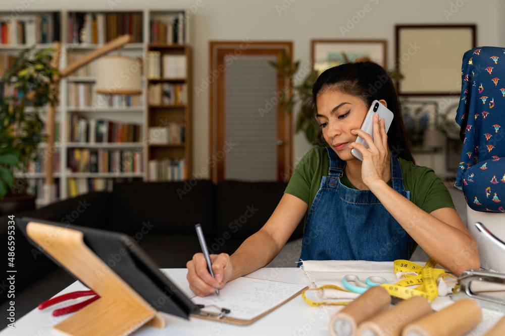 Asian crafswoman calling by phone at home office Asian crafswoman calling by phone at home office