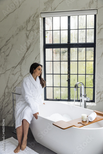 Woman sitting on the edge of tub in a bathrobe photo