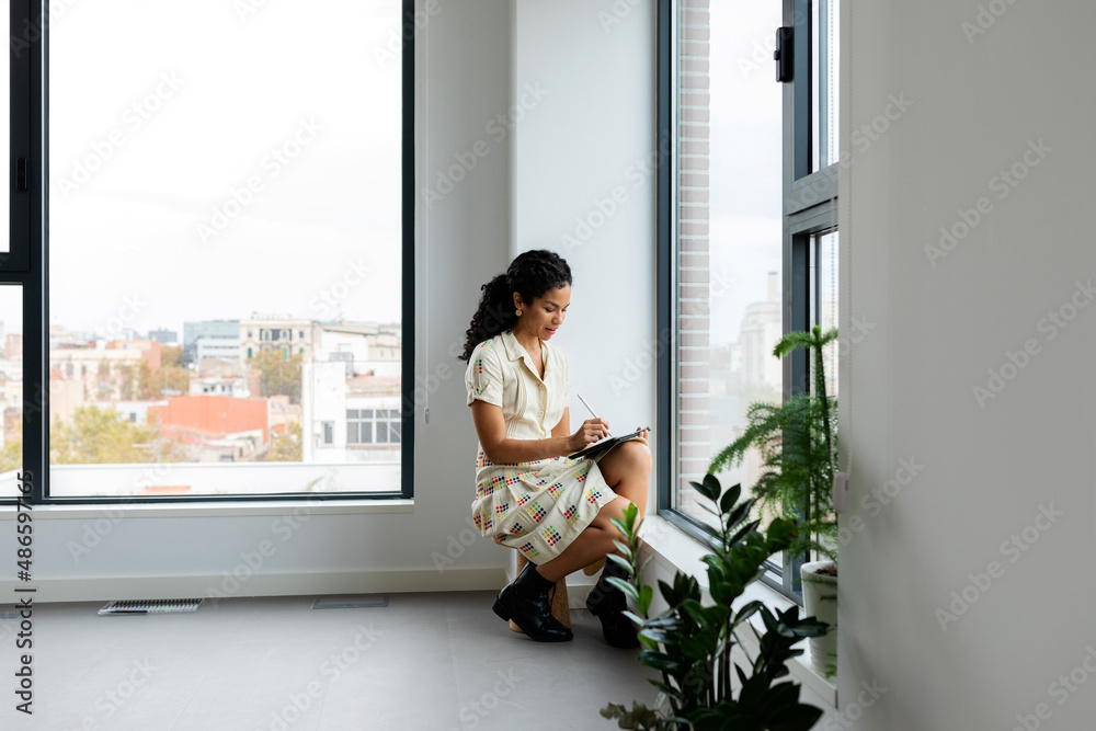 Woman using tablet near the window at studio Woman using tablet near the window at studio