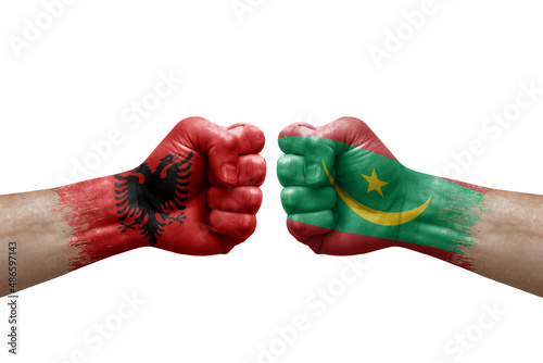 Two hands punch to each others on white background. Country flags painted fists  conflict crisis concept between albania and mauritania