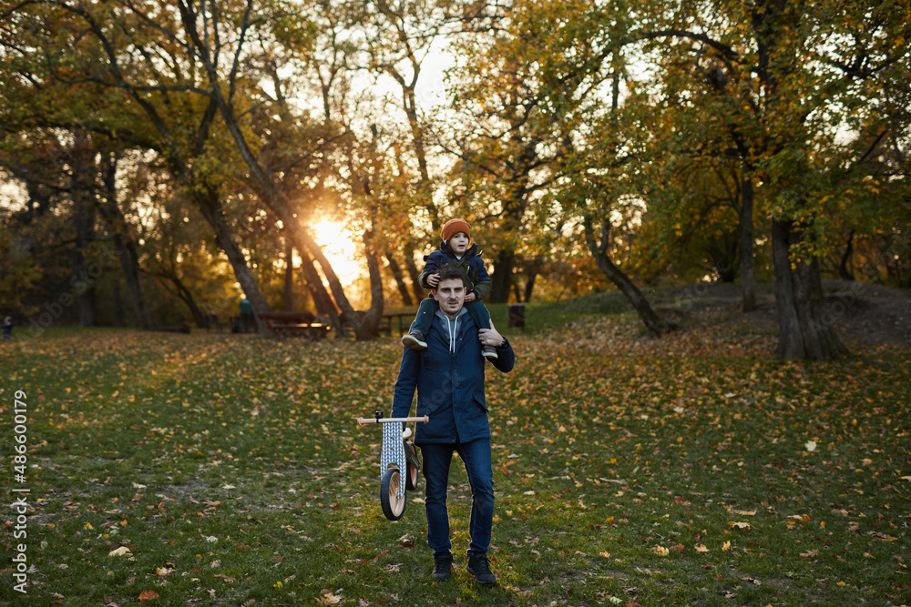 Man Carrying His Son And A Bicycle Through The Park Man Carrying His Son And A Bicycle Through The Park