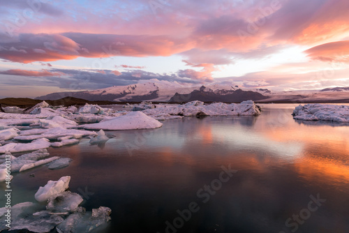 Fototapeta Naklejka Na Ścianę i Meble -  Dramatic sky glowing in midnigt light over a glacier lagoon. Jokulsárlón, Iceland.