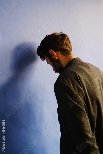 Young man turned to the purplish wall