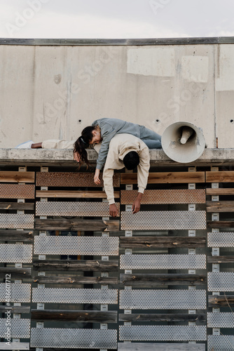 Friends laying down on top of wall next to megaphone photo