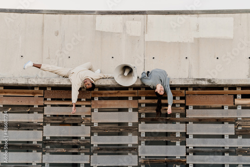 Friends laying down on top of wall next to megaphone photo