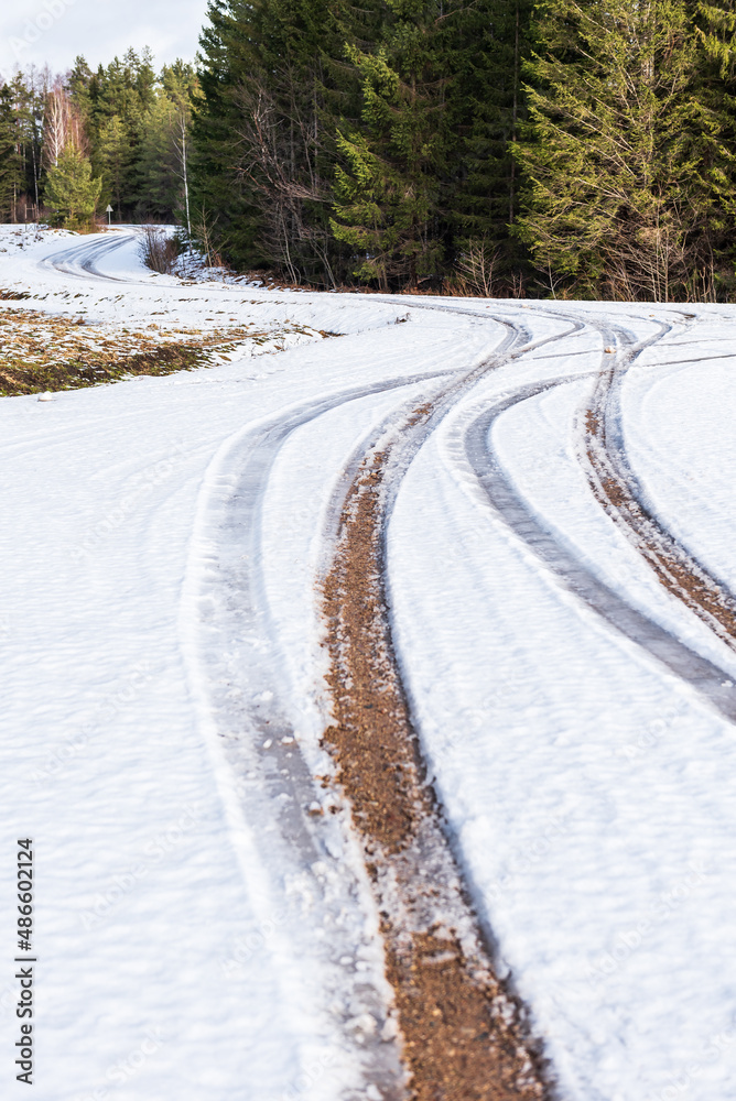 Winding gravel forest road in winter day, Latvia.