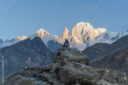 Man sits on rock and looks at Himalaya mountains photo