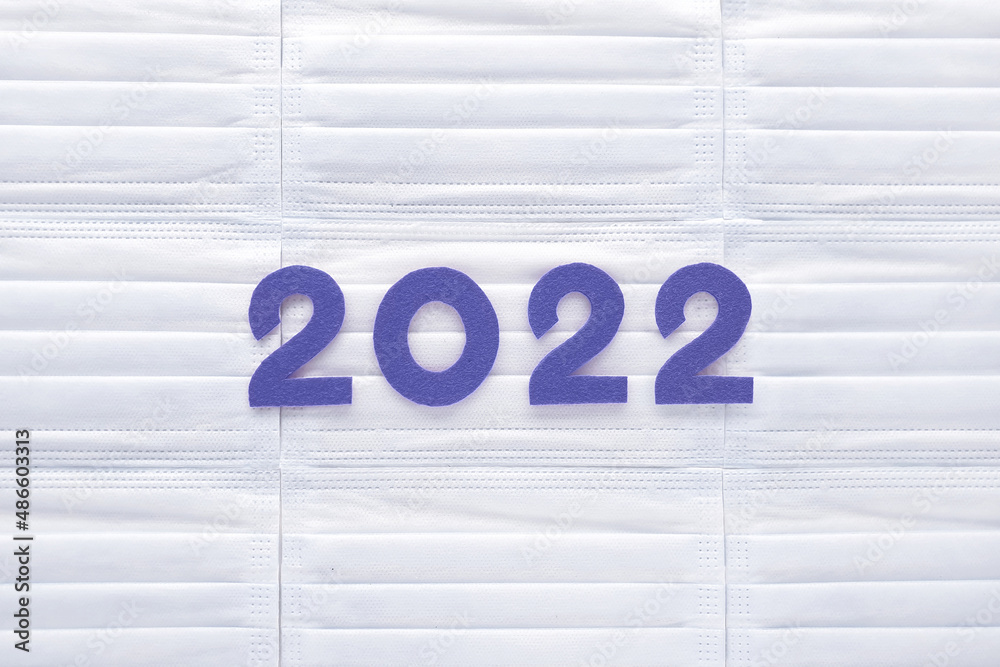Violet felt new year numbers 2022 on white medical masks background. Inspired by trendy very peri color of the year 2022. Place for your text here. - obrazy, fototapety, plakaty 
