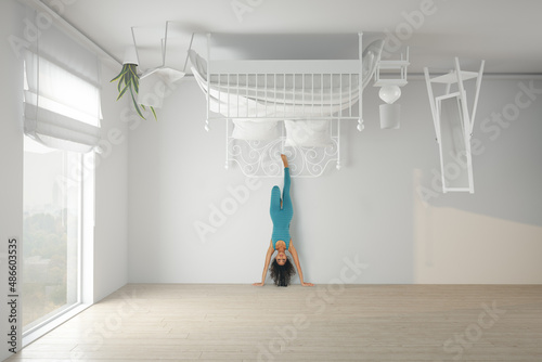 Woman doing a headstand in an upside down bedroom photo