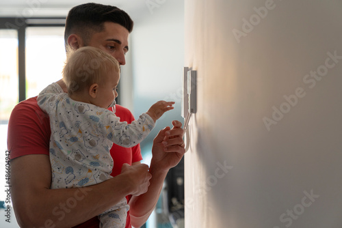 father with baby going to the intercom on the wall photo