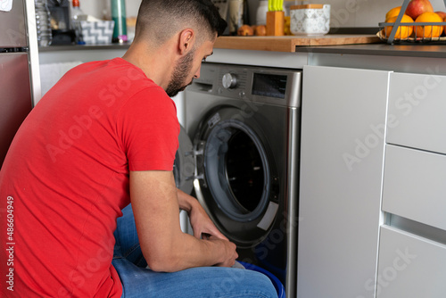 man picking up clothes from the washing machine photo