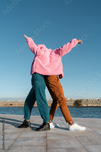 Friends sharing colorful jacket while dancing 