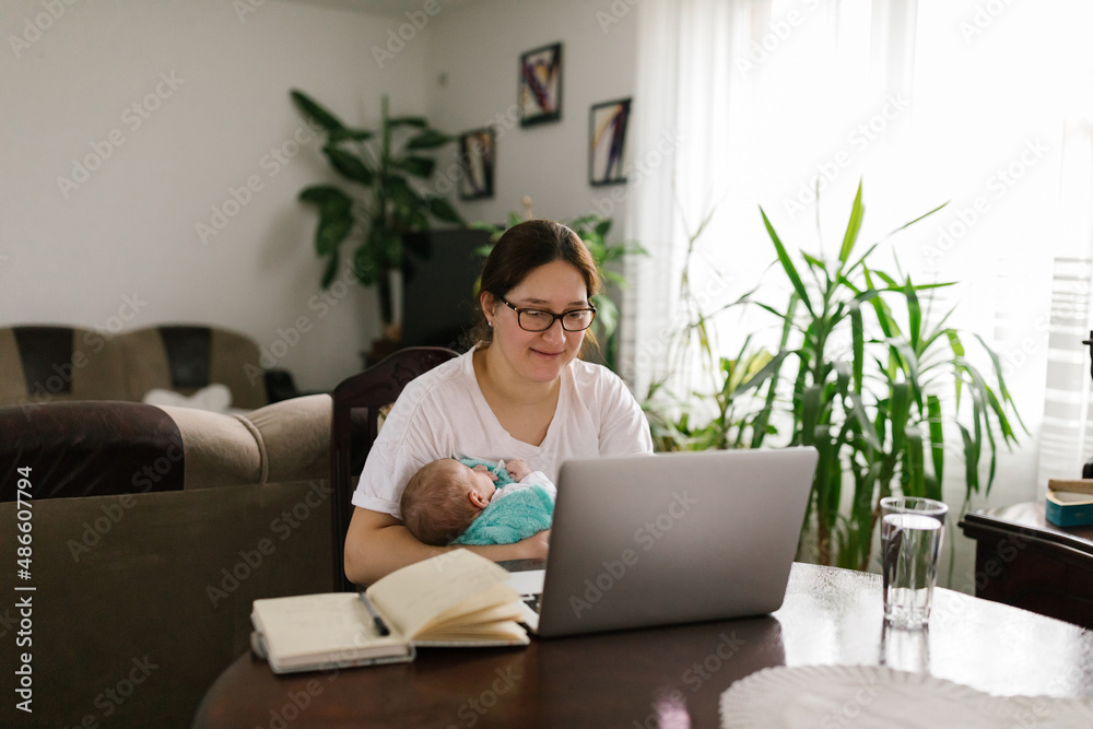 Smiling mom holding baby and FaceTiming via laptop Smiling mom holding baby and FaceTiming via laptop
