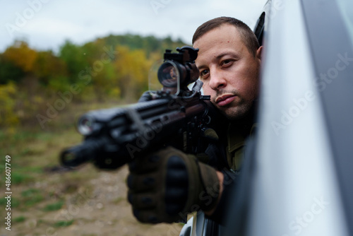One man special force police or terrorist holding automatic weapon shooting and aiming from the car anti-terrorist unit on the mission under attack in vehicle copy space side view © Miljan Živković