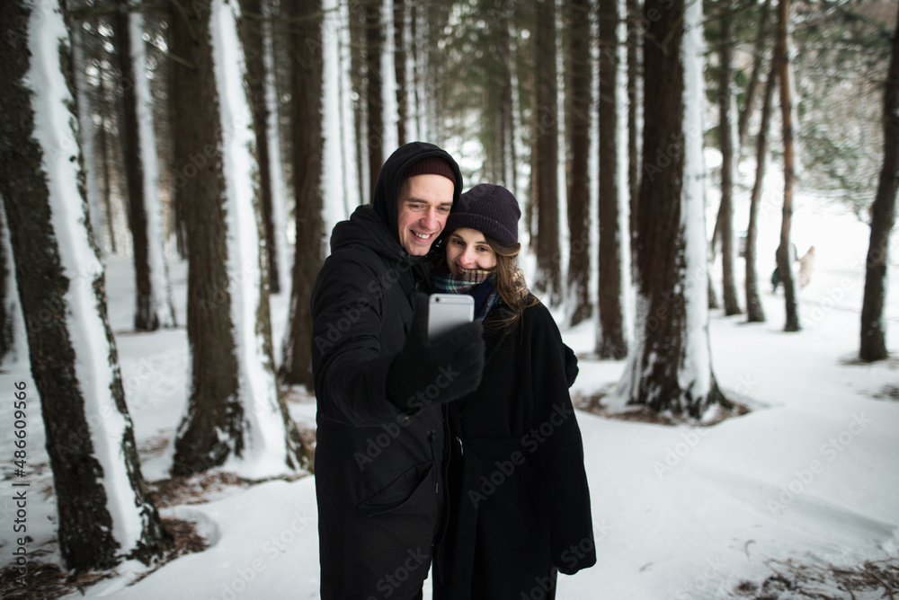 Man and woman taking selfie photo in the snowy forest Man and woman taking selfie photo in the snowy forest