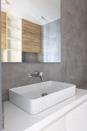White sink and mirror reflecting the bathroom