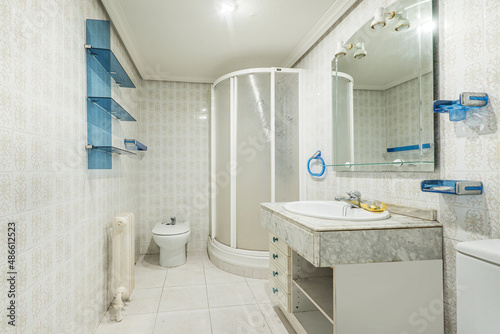 Toilet with kitsch vintage decoration with blue details, quarter-round shower cabin and marble countertop photo