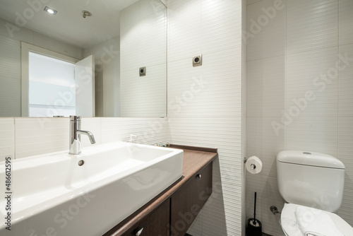 Bathroom with dark wood cabinets with drawers and white porcelain sink  rectangular frameless mirror